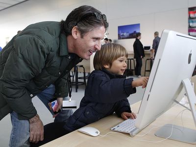 Apple employee Jason Roth (L) and his son Tyler Roth, 3, play with an iMac