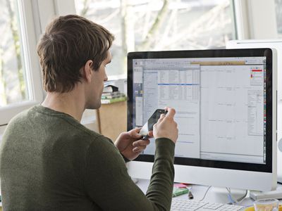 Man looking at mobile phone and PC