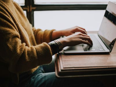 A person using a laptop next to a window