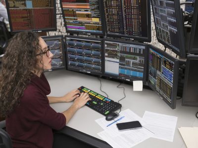 An IT support specialist types at a Bloomberg terminal with eight monitors.