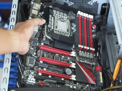 Holding a motherboard in an open computer case.