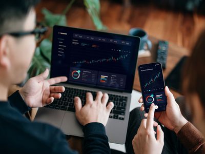 Business people looking at financial data on a laptop and smartphone using AI.