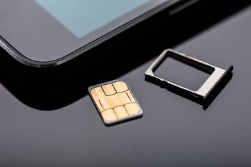 A SIM card next to a smartphone.