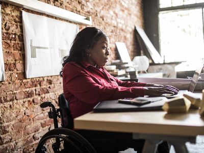 A woman sitting at a desk looking at her laptop