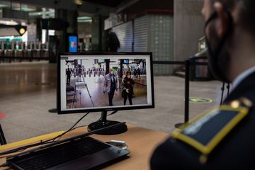 Man looks at monitor with closed laptop nearby.