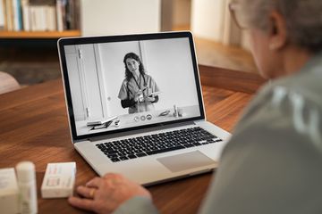 A woman using a laptop with a black and white screen.